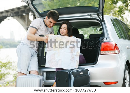 Young family looking at map near the car outdoors