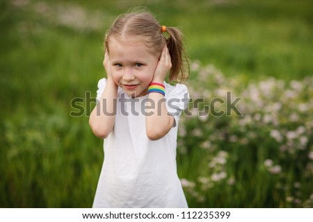 Hear no evil - Lovely little girl covering her ears with hands, doesn\'t want to hear anything, outdoors