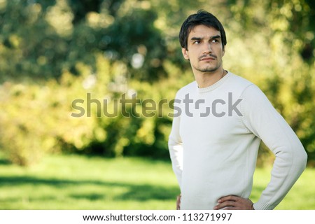 Young handsome man outdoors in fall clothing with autumn natural surroundings looking to the side, with copy space