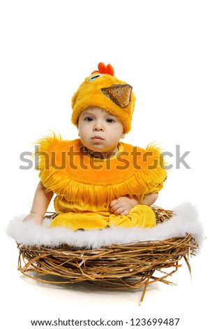 Baby sitting in nest in chicken costume, isolated on white background. Easter holiday concept.