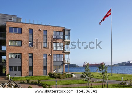 Modern five-storey house on the sea shore with Norwegian flag, Norway, sunny summer day