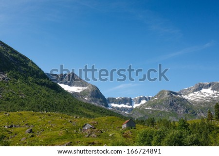 Norwegian landscape with mountain and gray hut on foreground