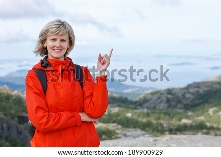 Happy woman outdoors pointing up at copy space