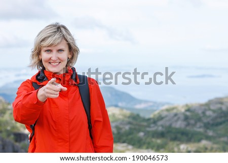 Happy woman tourist pointing finger at you against nature background outdoors