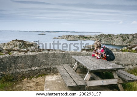 Woman enjoying ocean view sitting on table for picnic, Norway