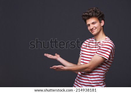 Smiling handsome man showing open hand palm with copy space for product or text
