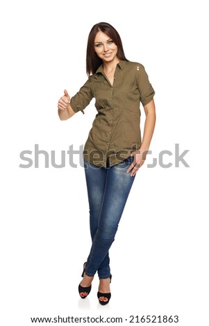 Full length of young smiling female in jeans and green shirt giving you thumb up over white background
