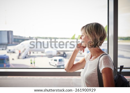 Closeup of a woman at the airport window looking to the airplane