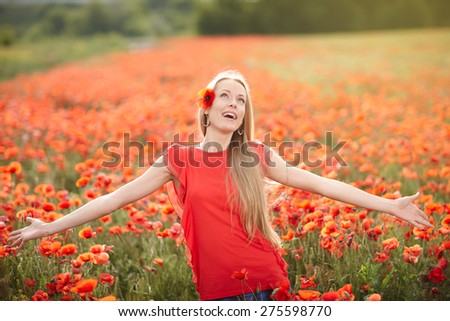Lovely woman feeling happy on the poppy flower field. Beautiful woman in happiness and elated enjoyment with arms raised outstretched up enjoying nature, summertime leisure concept.