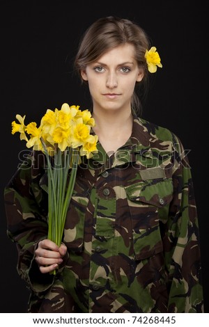 Young female in male military chemise holding bunch of flowers