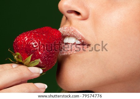 Closeup of female  lips in sugar with strawberry, shallow deep of field, focus on strawberry