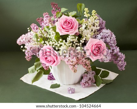 Artistic still life with huge bouquet of lilac and lily of valley flowers and roses on painting background