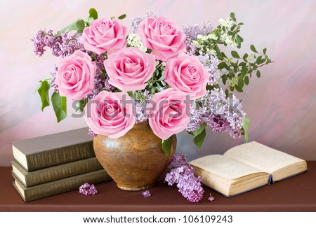 Beautiful still life with lilac and pink roses flowers bouquet, books pile and open book on painting background