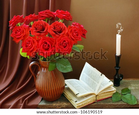 Still life with huge red roses bunch, open book and candle on artistic background