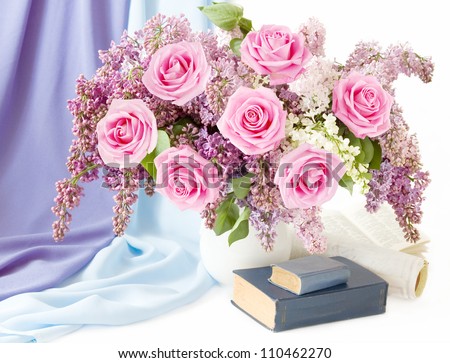 Still life with huge bunch of lilac flowers and pink roses, books and material drapery om white background