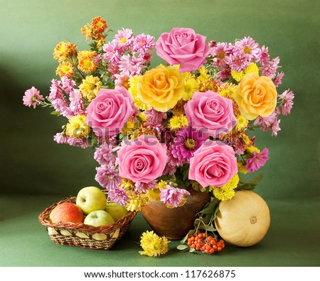 Still life with autumn flowers and roses, apples, rowan and gourd on artistic background