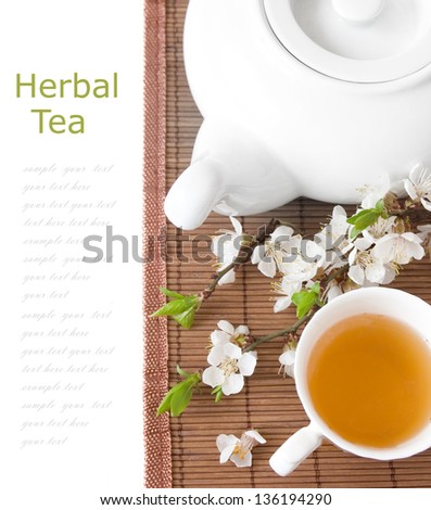 Herbal tea (tea breakfast with kettle, cup and blossom flowers  on bamboo mat isolated on white with sample text )