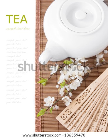 Herbal tea (tea breakfast with kettle, blossom flowers on bamboo mat and fan isolated on white with sample text )