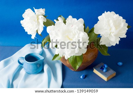 Still life with peony bunch, book, color stones and spot on artistic background
