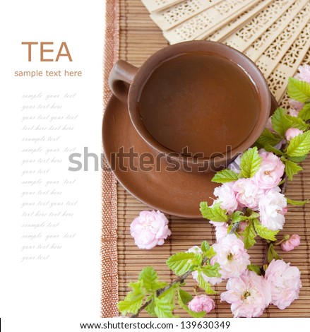 Tea breakfast (cup of tea with fan and blossom tree branch on bamboo mat isolated on white background with sample text)