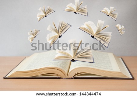 Books flying away from open book on the desk. Education concept