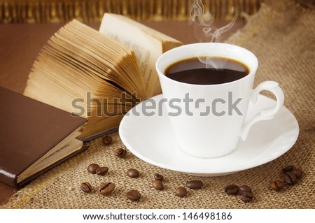 Coffee break (cup of hot coffee, books and coffee beans on artistic background)