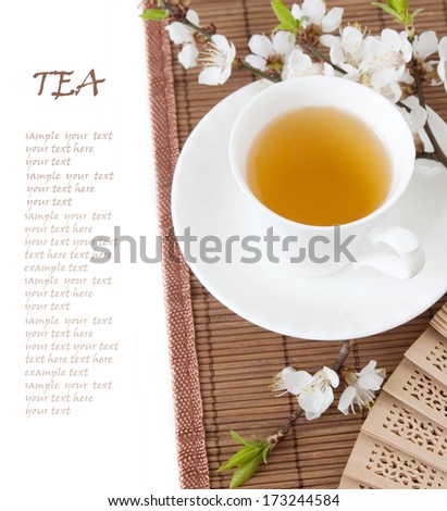 Herbal tea (tea breakfast with cup of tea and blossom flowers on bamboo mat isolated on white with sample text )