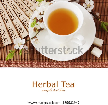 Herbal tea (cup on tea, sugar, wooden fan and blossom tree flowers on mat isolated on white background with sample text)