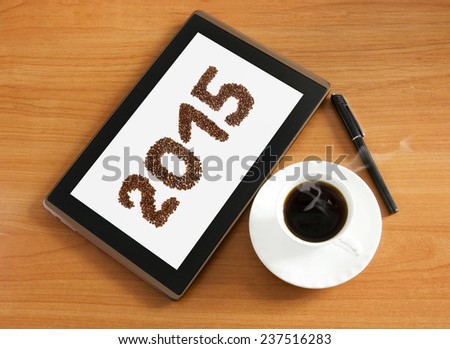 Working place with pen, coffee cup and tablet pc on wooden desk. New year concept