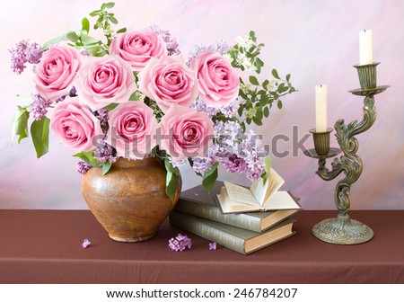 Still life with roses and lilac flowers, books and candlestick on artistic background