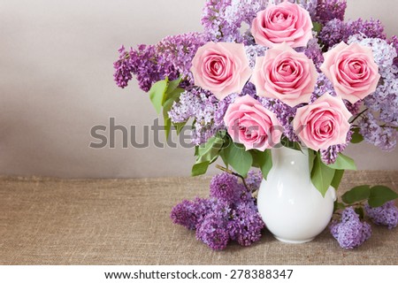 Lilac and roses bunch in vase on artistic background