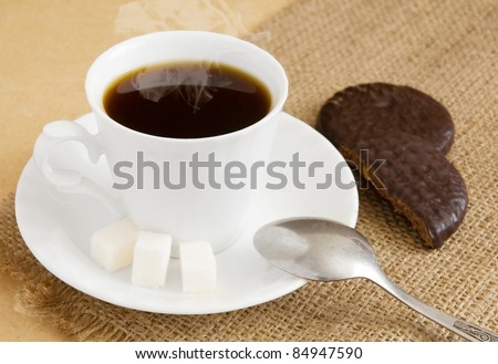 Cup of hot coffee with sugar, chocolate cakes and metal spoon