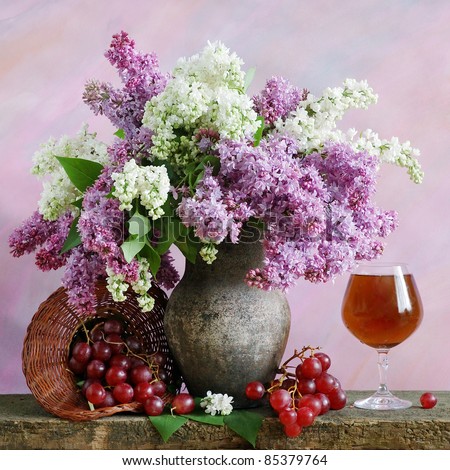 Still life with lilac, grapes and red wine on painting background