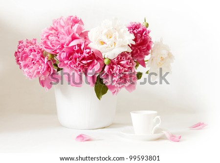 Artistic still life with peonies and cup of coffee and petals