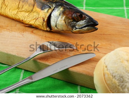 smoked fish on a cutting board with bread and cuttlery