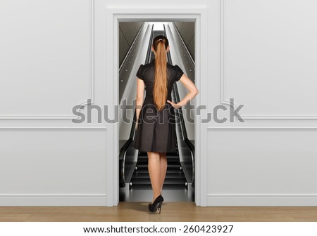 Girl standing back to doorway going on escalator.