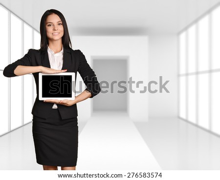 Office girl standing on background of light interior and showing screen tablet.