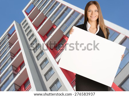 Business woman holding blank poster on background of building.