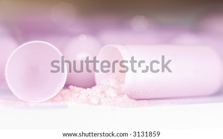 Extreme close-up of an opened pink capsule filled and poured pink powder.