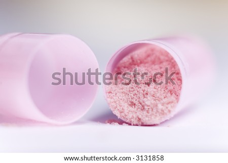 Extreme close-up of an opened pink capsule filled with pink powder.