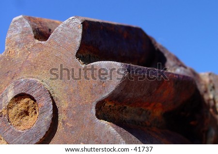 An old rusted gear with great texture and a sky background.