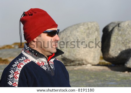 A handsome middle age hispanic latin man in a top of a mountain with winter clothing