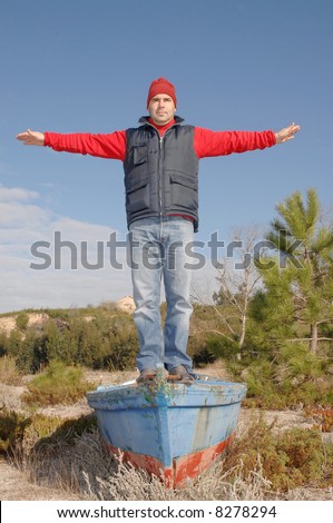 handsome middle age man in a titanic position, open arms on top of a boat