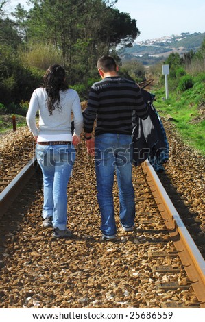 A young couple walking on a railway track