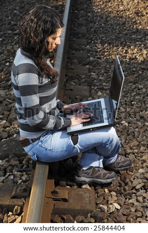 pretty girl waiting for the train on a railway with a laptop, computer