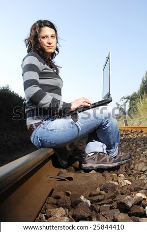 pretty girl waiting for the train on a railway with a laptop, computer