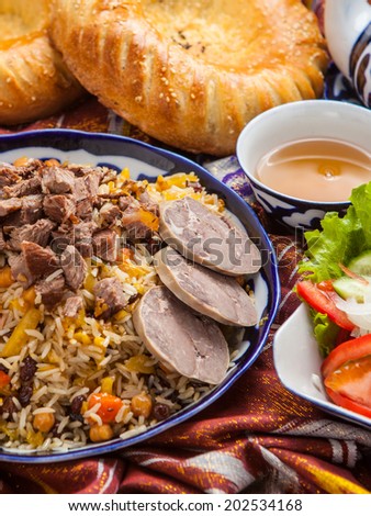 Uzbek national food pilaf with bread, tea, salad on adras.