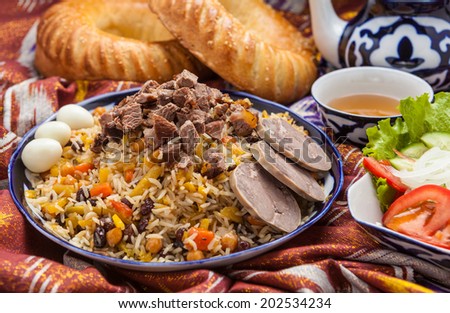 Uzbek national food pilaf with bread, tea, salad on adras.