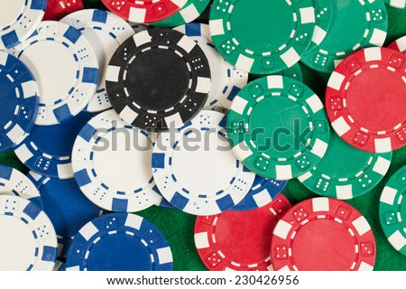 Green, red, blue, white and black Playing Poker Chips in a green background