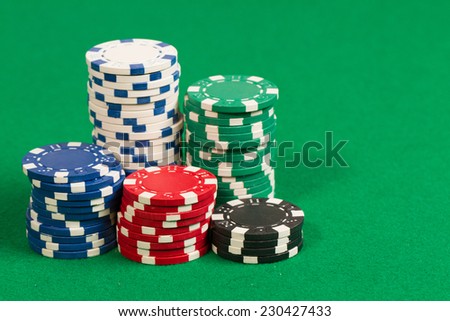 Stack of green, red, blue, white and black Playing Poker Chips in a green background